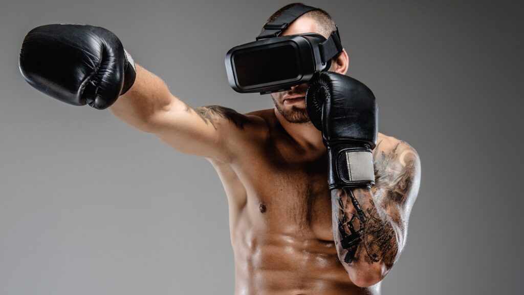 Shirtless brutal boxing fighter in virtual reality glasses. Shirtless brutal boxing fighter in virtual reality glasses on his head. Isolated on a grey background.